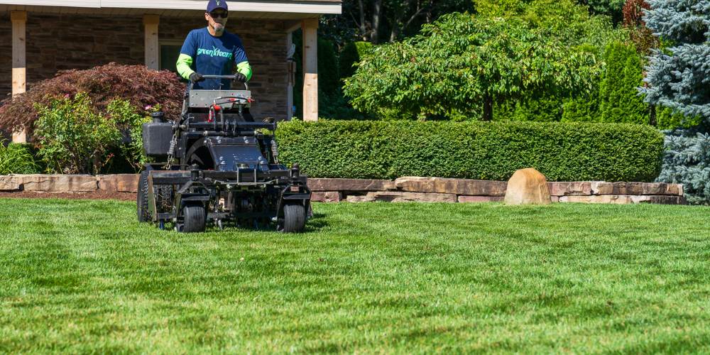 landscape expert aerates lawn on machine