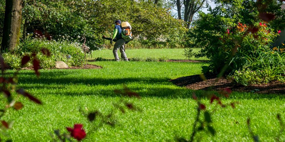 pest control technician sprays perimeter of yard for ticks